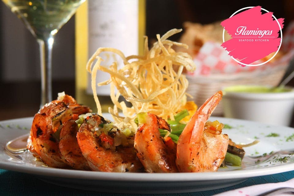 A beautifully plated shrimp meal withe a cocktail at Flamingos Seafood Kitchen, one of the best restaurants in Cancun with kids.