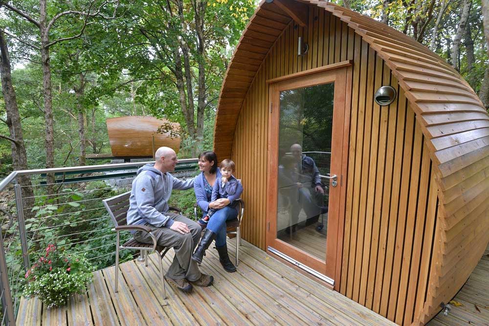 Mom and dad with little boy on their lap in front of glamping cabin