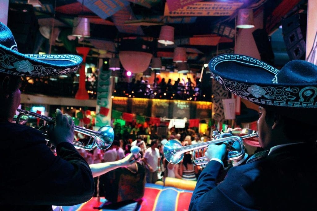 Behind two mariachi band members playing instraments, behind them is a large room of diners at Señor Frogs, one of the best restaurants in Cancun with kids.