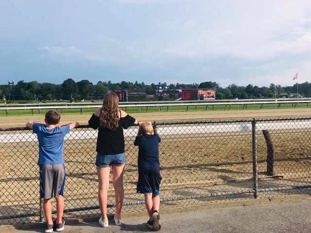 Three kids at racetrack in upstate New York watch from the sidelines.