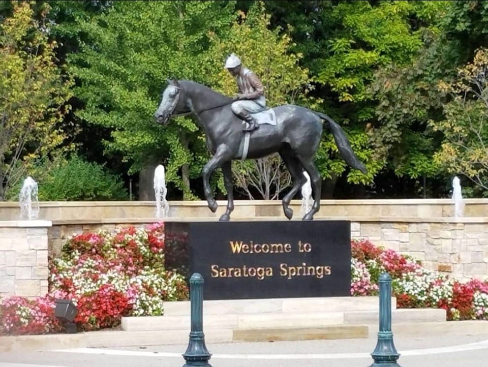 The "Welcome to Saratoga Springs" sign, atop of which sits a horse and rider statue, one of the best cute towns near NYC with kids.