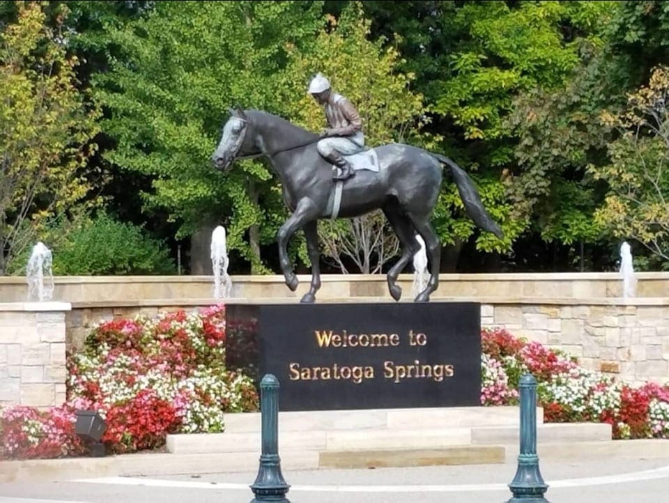 The "Welcome to Saratoga Springs" sign, atop of which sits a horse and rider statue.