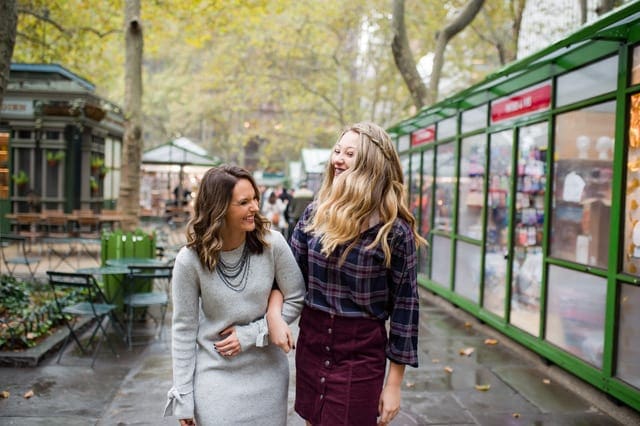 Mom and daughter walk arm and arm down the street laughing, while vacationing in Bryan Park Manhattan.