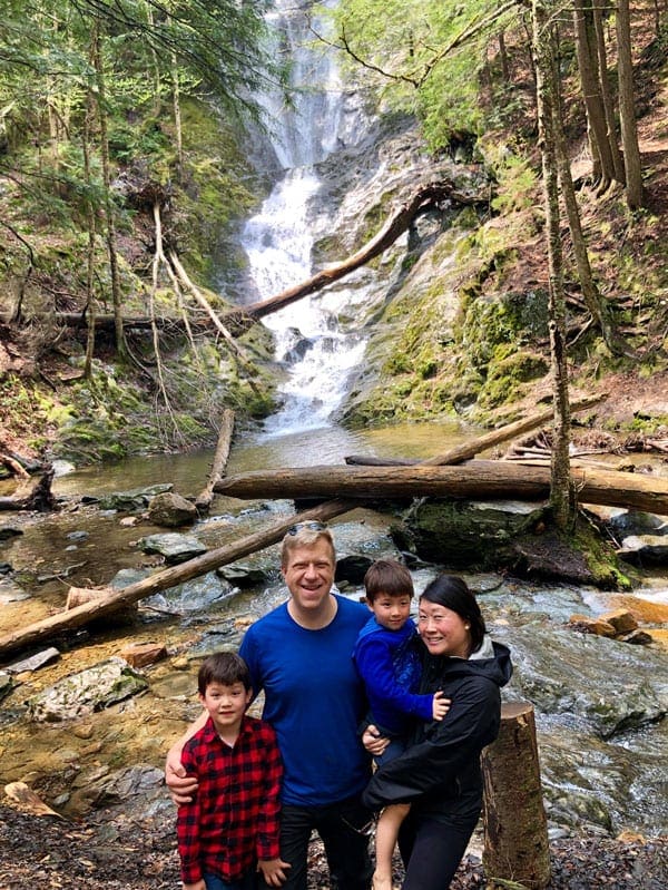 Family of four in front of waterfall in the forest near the Great Barrington, one of the best places to visit during Memorial Day Weekend near NYC for families.