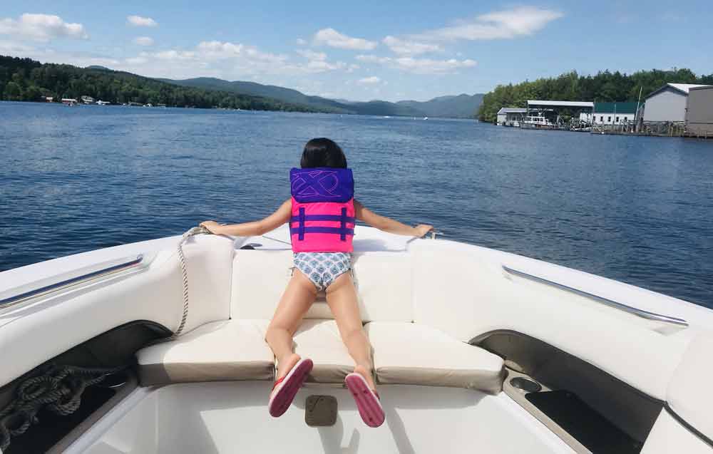 Little girl on boat looking at water at Lake George, one of the best Labor Day Weekend getaways near NYC with kids.