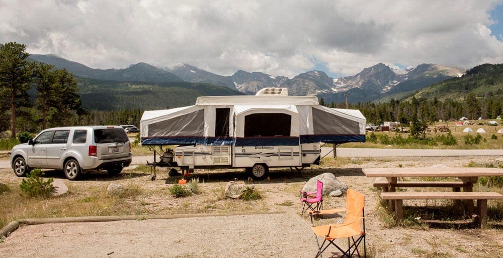 A RV parked at a campsite, near the mountains