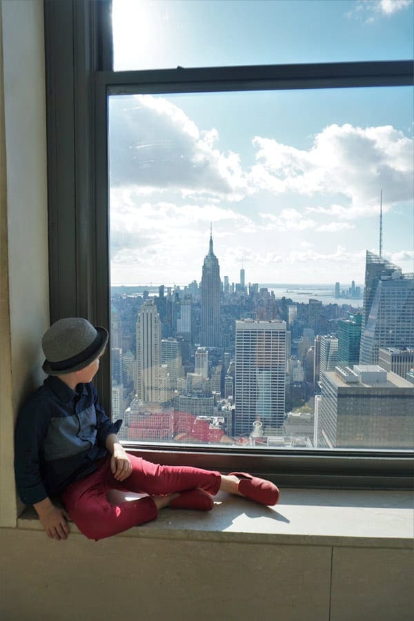 Little boy looking at NYC skyline from window in the Empire State Building.