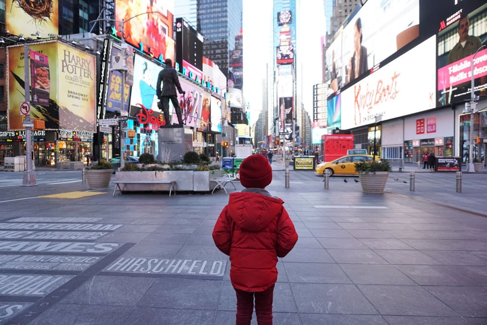 Little boy wearing red in Times Square, one of the best things to do when learning all about New York City with kids.