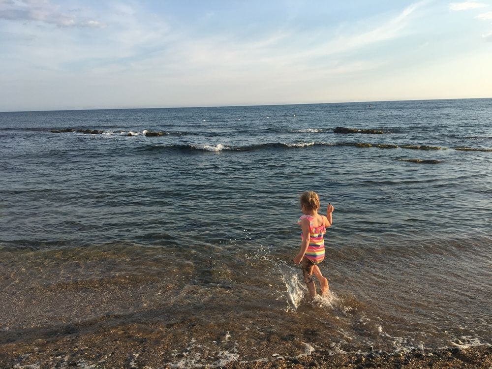 Child in walking into the water at a public beach in Santa Marinella, one of the best things to do near Rome with kids.