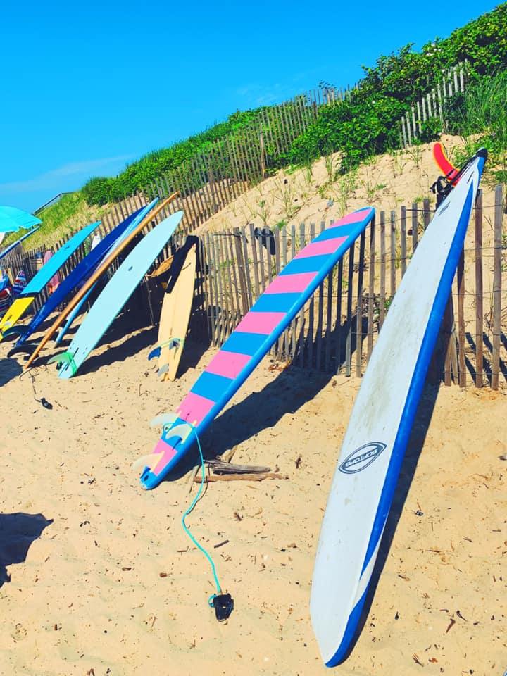 Several colorful surfboards rest along a fence at Montauk Beach, one of the best East Coast summer destinations for families.