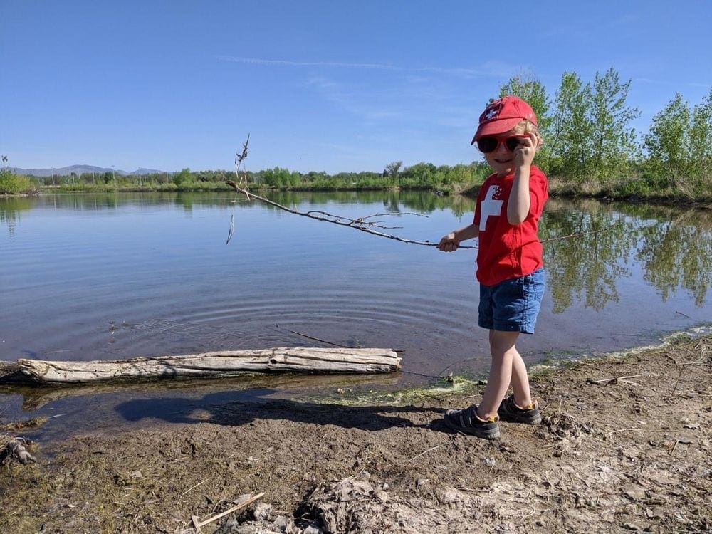 Small boy stands near a lake while on one of the best family hikes near Denver.