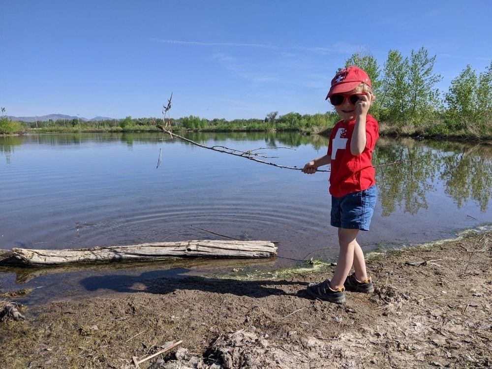 Small boy stands near a lake while hiking near Denver. Hiking is one of the best things to do on a Denver itinerary for families!