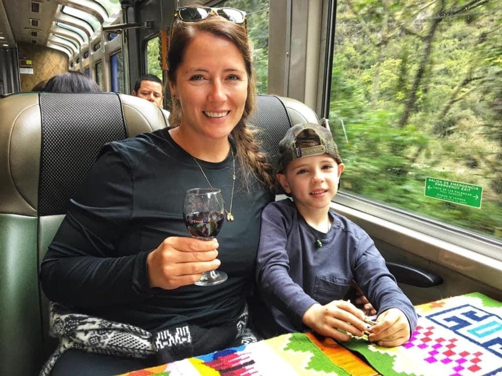 Mother and son sit smiling on a train within the Sacred Valley area of Peru