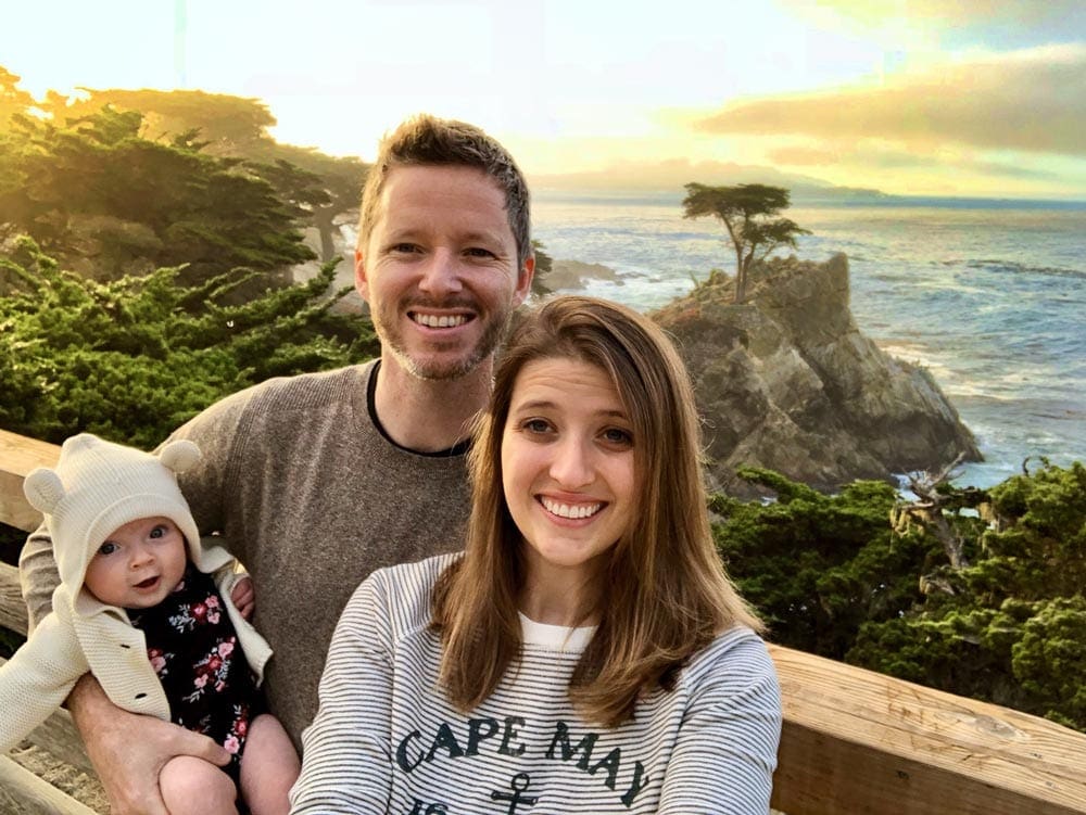 Family of three stands in front of the ocean in Big Sur, one of the best places to visit in the US during Easter Break with kids!.
