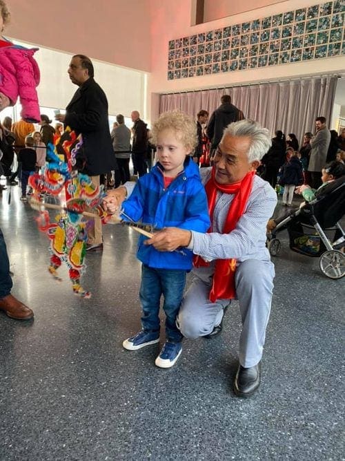 Older gentleman shows a young child how to use a Chinese puppet at the Kennedy Center.