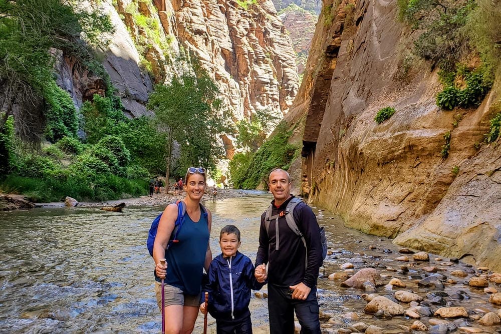 Family of three stands in a canyon at Zion National Park, one of the best places for families in the U.S.