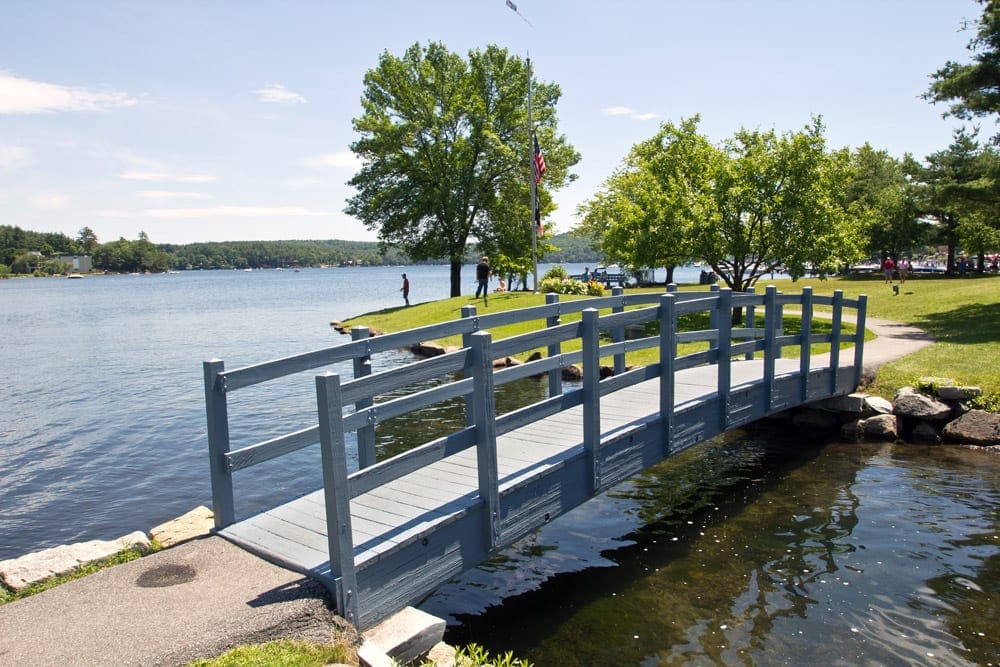 Bridge on the Lake Winnioesaukee with lush green trees,  one of the best US lakes for families.