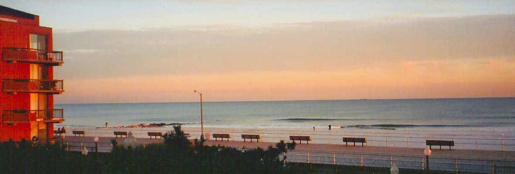 Long Island Beach, one of the best family beach trips near NYC, with benches and a buildings dotting the view during sunset.