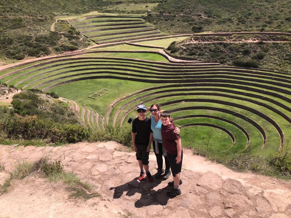 Mom and two kids stand above an ancient ruin in Moray, Peru, a great day trip on our Peru family vacation itinerary.