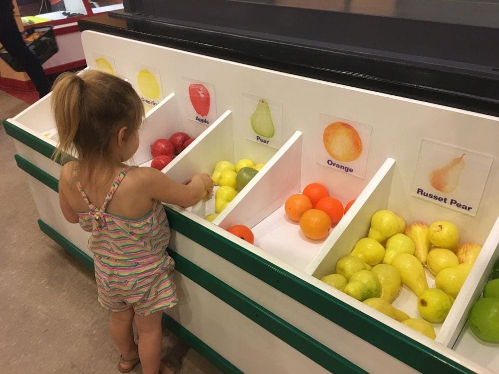 Child playing with toy fruit at the Please Touch Museum in Philadelphia, one of the best Philadelphia attractions for families.