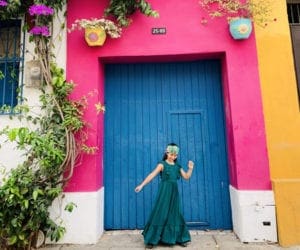 Girl dancing in front of colorful door in Colombia Caragena