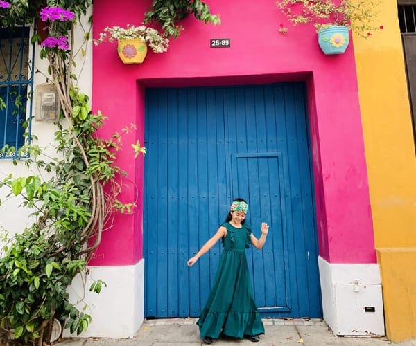 Girl dancing in front of colorful door in Colombia Caragena