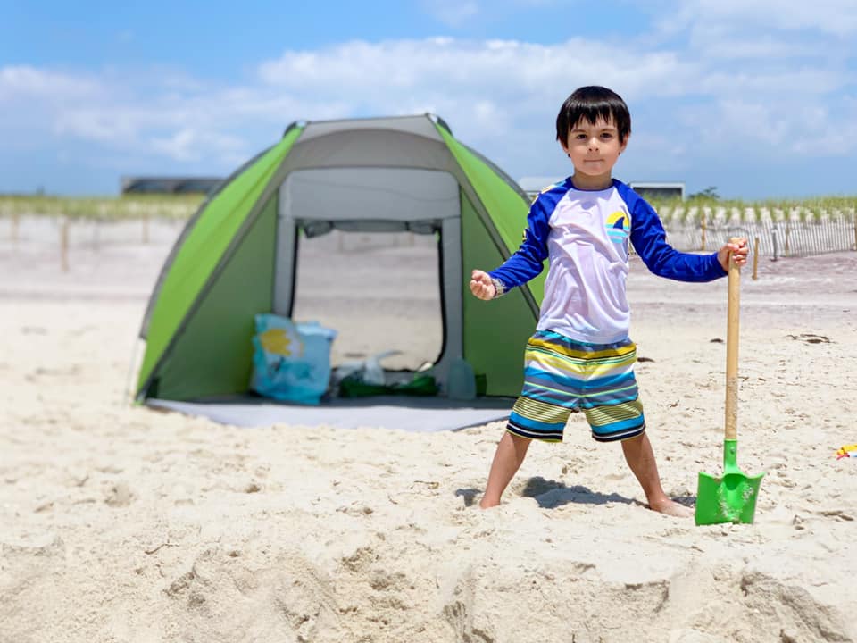 Little boy in front of the beach tent on fire Island beach, one of the best family beach trips near NYC.