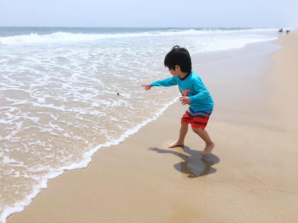 Little boy on the beach in The Hamptons, one of the best beach towns on the East Coast with kids.