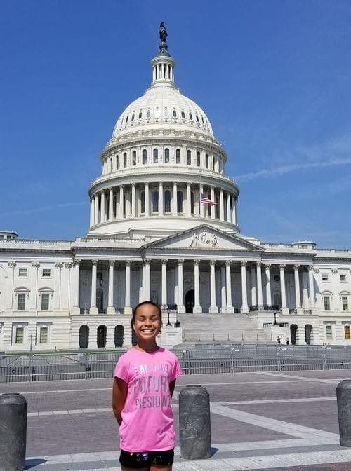A young girl stands proudly in front of the U.S. Capitol Building.