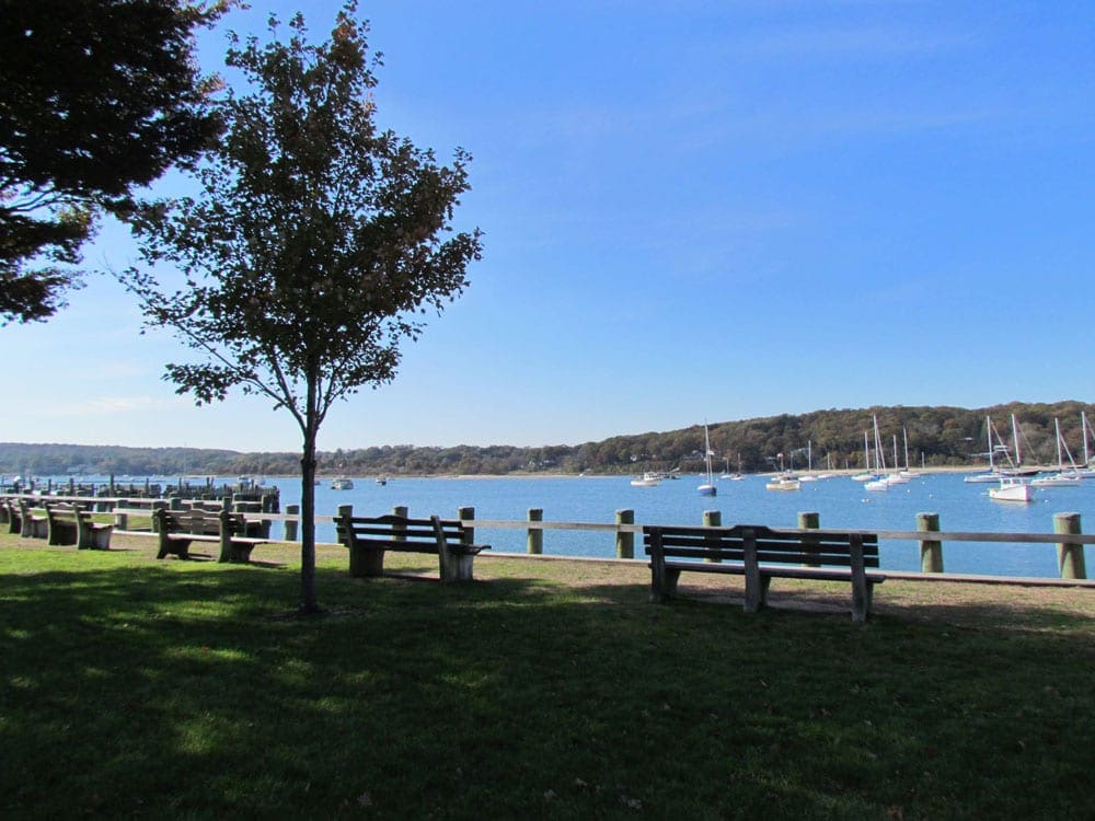 A view of several benches facing the water at the Village of Northport, one of the best family beach trips near NYC.