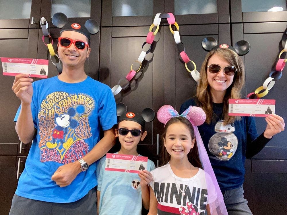 Family of four stands amongst Disney decorations as they prepare to have a Disney theme night at home.