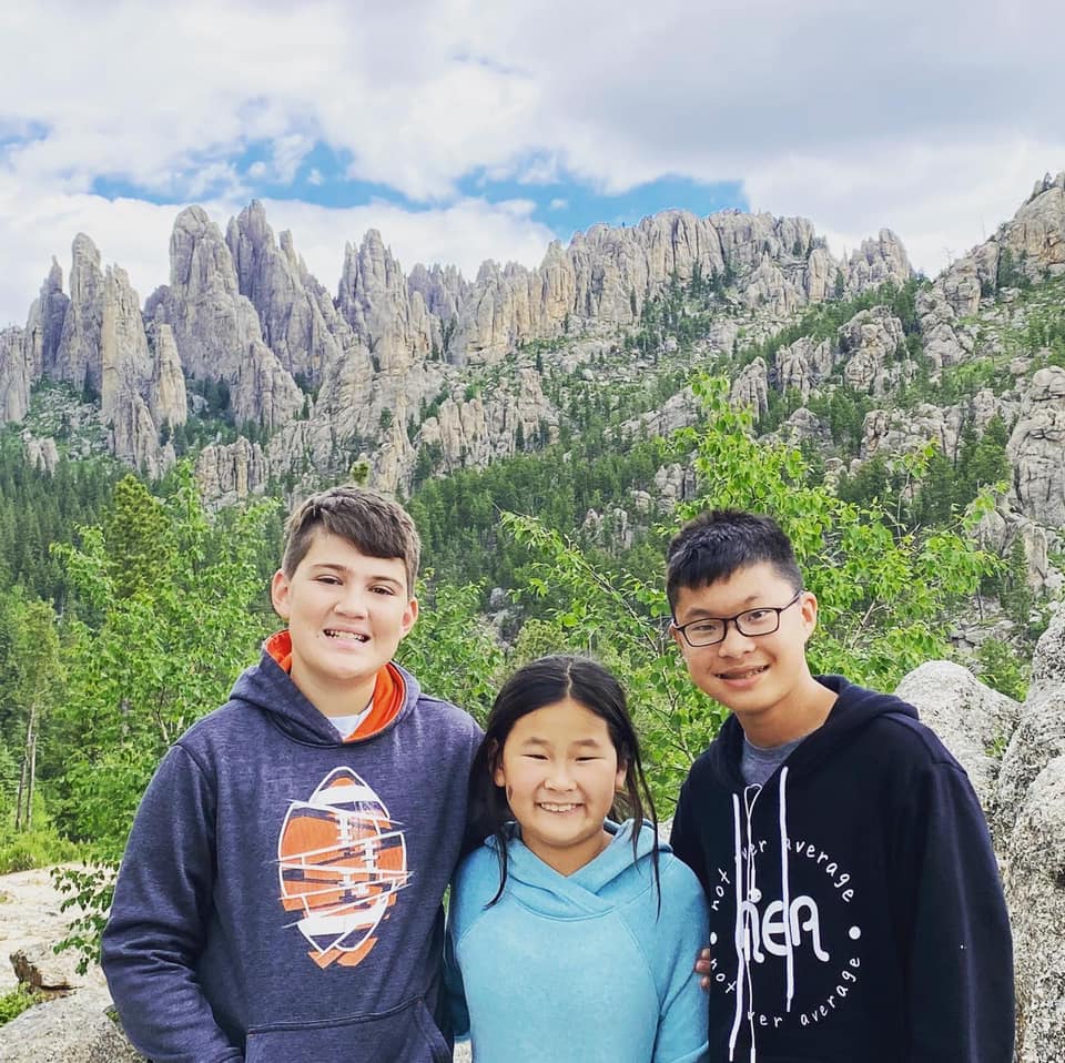Three siblings posting for a photograph with beautiful mountain view at the background