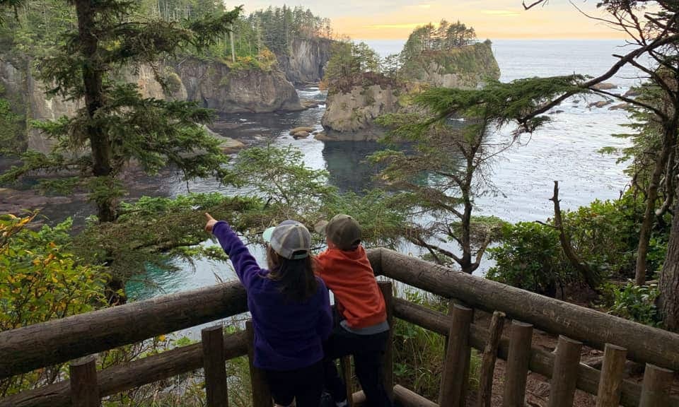 Two kids look over the bay at Crater Lake, the young girl points to something in the distance.