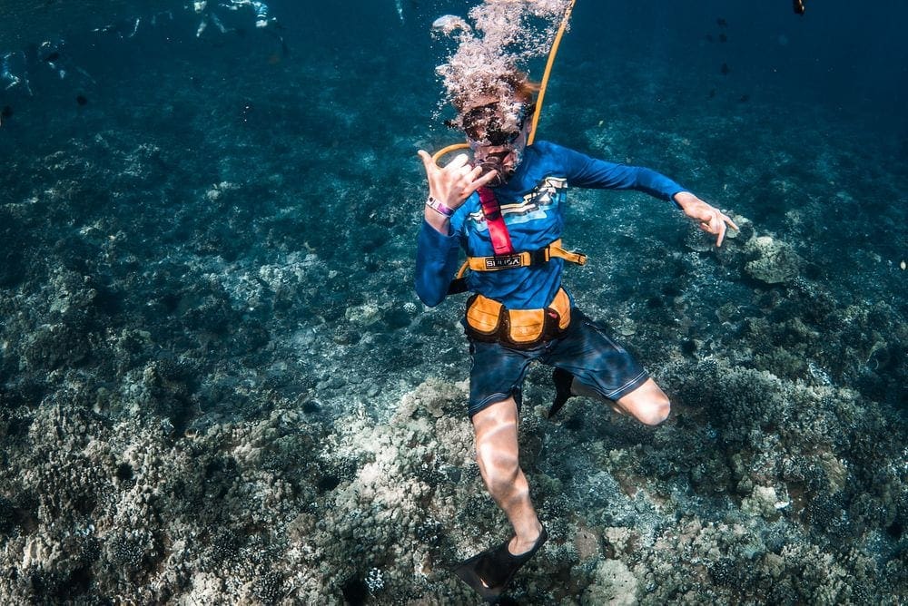 A scuba diver gives the "hang ten" symbol while underwater.