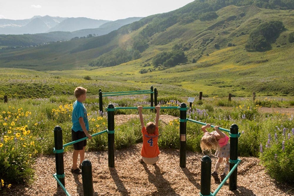 Three kids play in a roadside playground. 