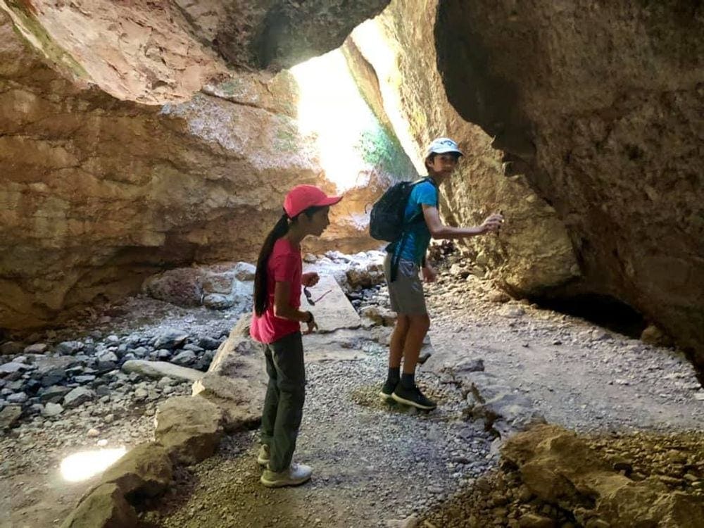 Two kids explore large rocks within Pinnacles National Park, one of the best west coast national parks for kids!