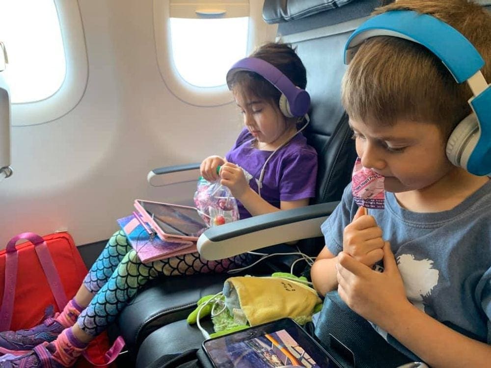 Two young kids enjoy suckers on an airplane, which are a great way to keep kids entertained while traveling.