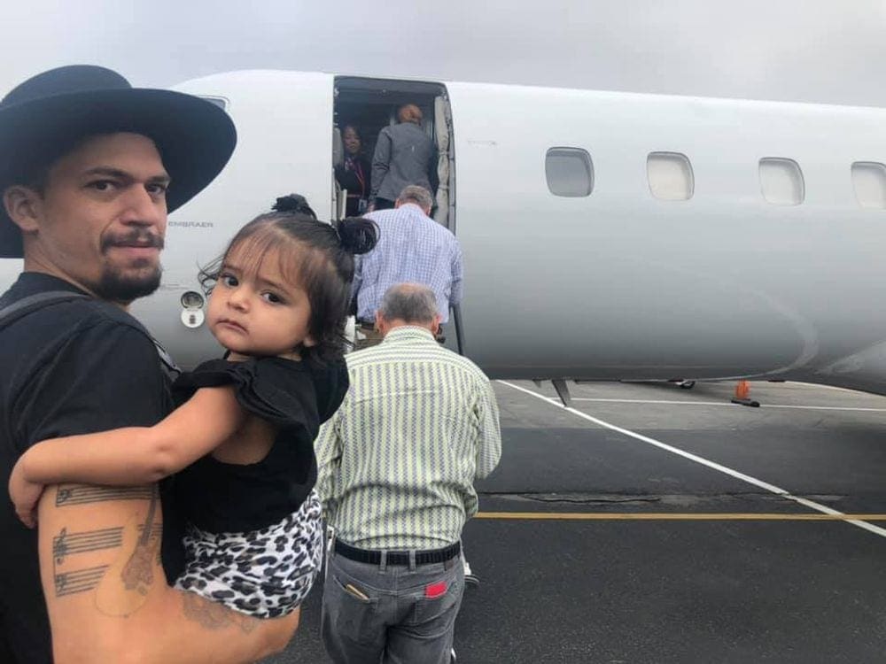 Dad and baby look back as they queue to board a plane on the tarmack.