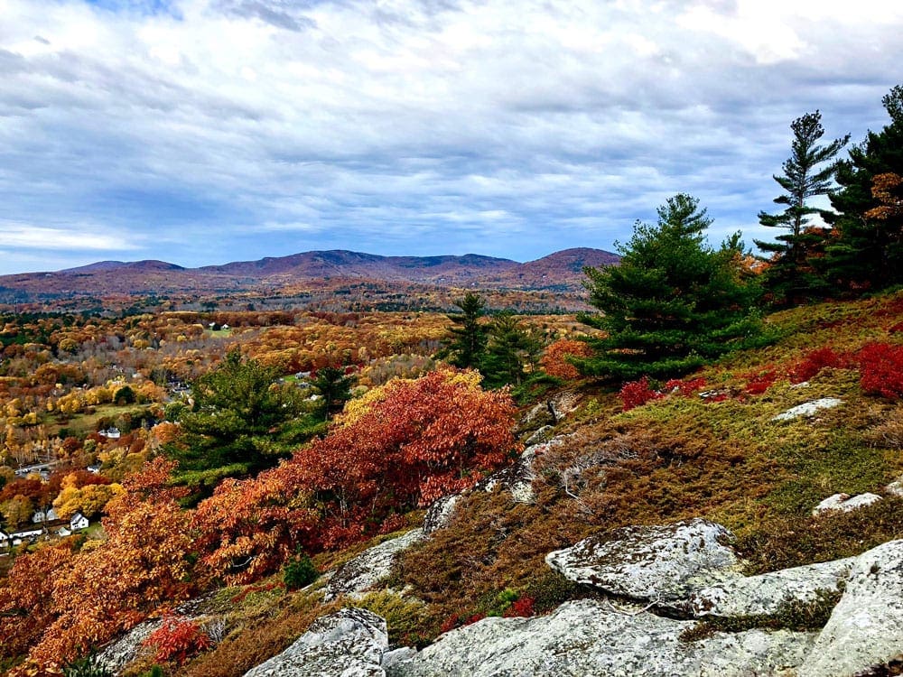 A white rock juts from a colorful fall scene within Camden Hills State Park, one of the best places to visit for fall in New England with kids.