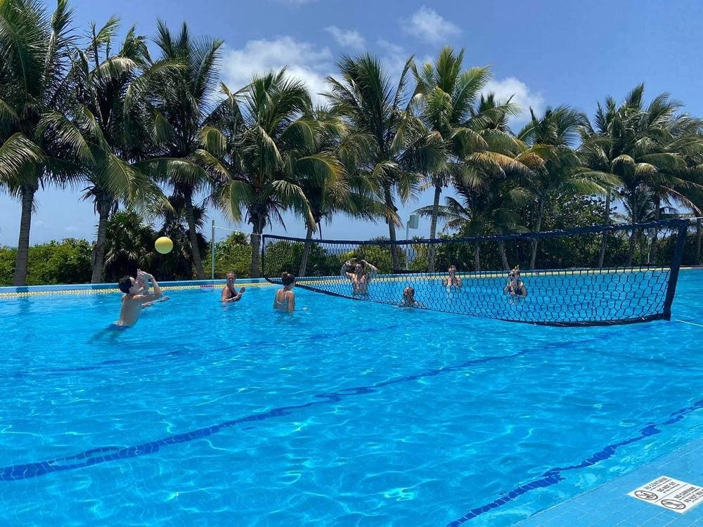 Two teams of four people play water volley ball in a pool at the Grand at Moon Palace Hotel in Cancun, one of the best family resorts Cancun.