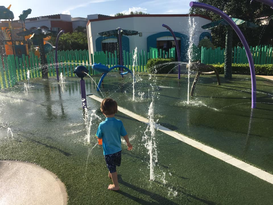 A young boy plays among the water in a splash pad near the beach at the Hard Rock Hotel Cancun, one of the best family resorts Cancun.