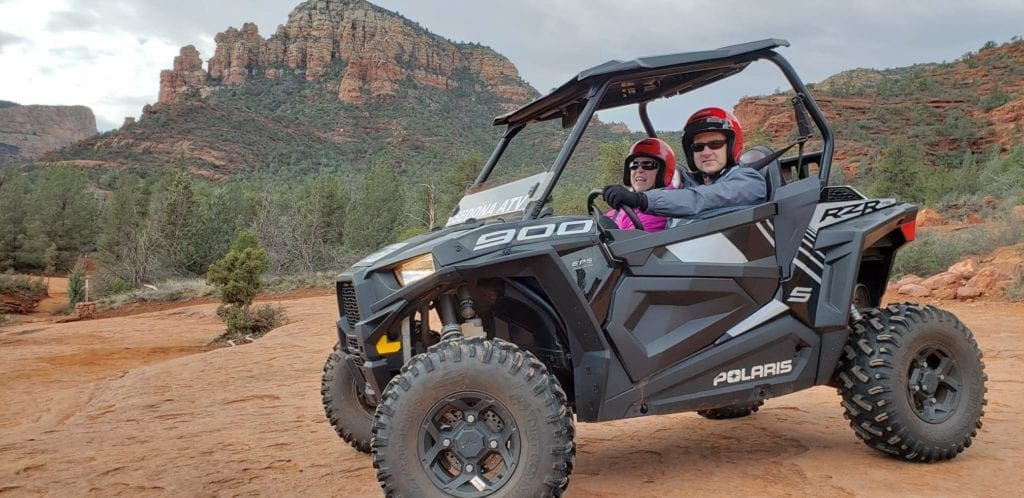 Two adults sit in an ATV exploring the Sedona desert, a must see on any Sedona itinerary for families.