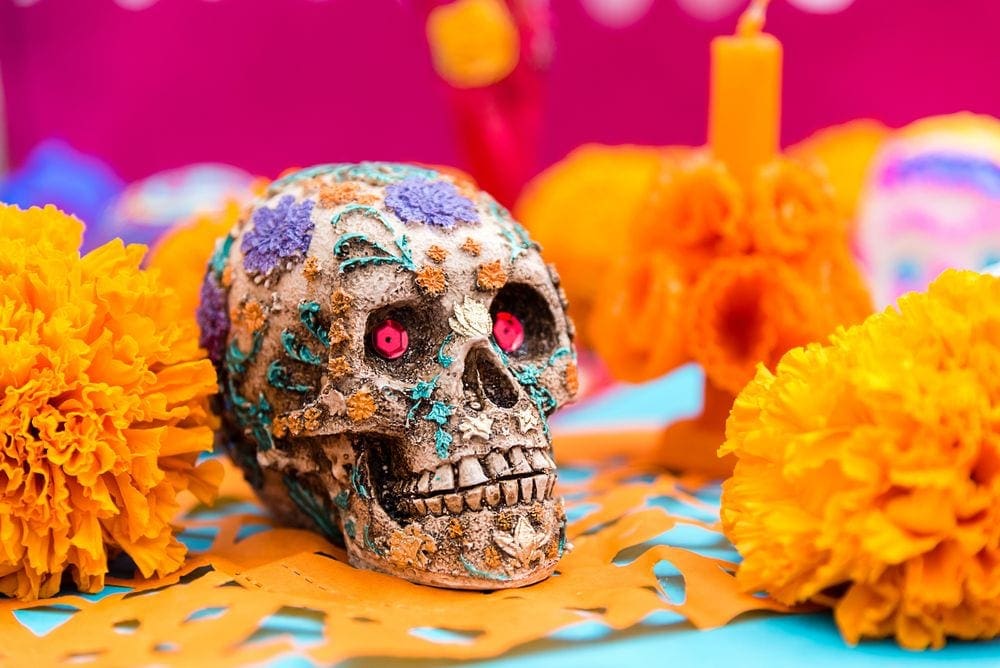 A brighly colored sugar skull rests among marigolds as part of a Day of the Dead display in Cabo San Lucas, one of the best places to go for Halloween.