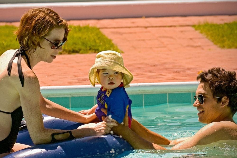 A mother, father, and child enjoy a sunny day at the pool at The Tyler Place Family Resort, one of the best Vermont hotels for families.