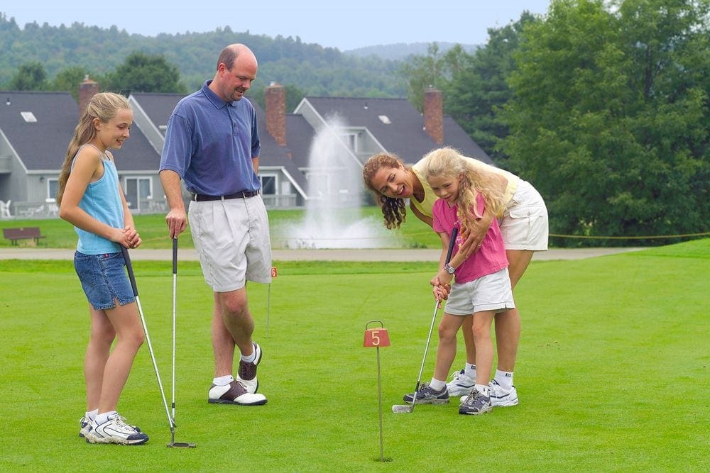 A family of floor plays golf at the Stoweflake Mountain Resort & Spa, one of the best Vermont hotels for families.