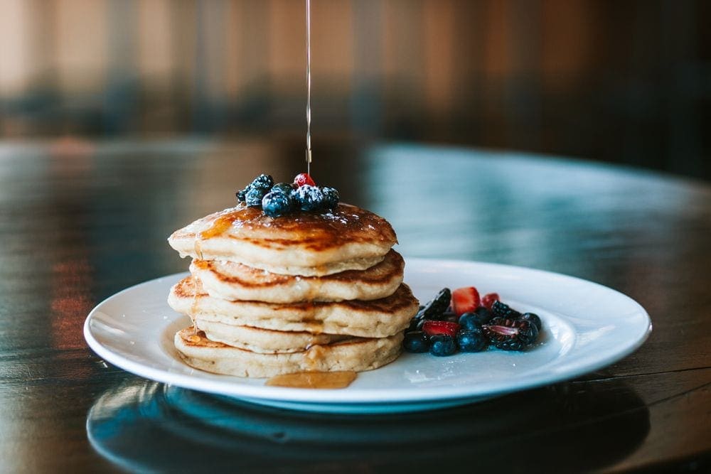 Syrup rains down on a perfect stack of pancakes at Topnotch Resort, one of the best Vermont hotels for families.