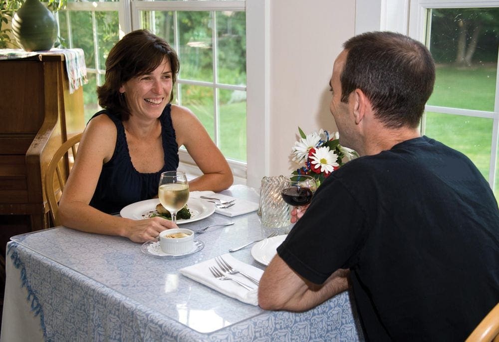 A husband and wife sit at a table enjoying a quiet meal at The Tyler Place Family Resort, one of the best Vermont hotels for families.