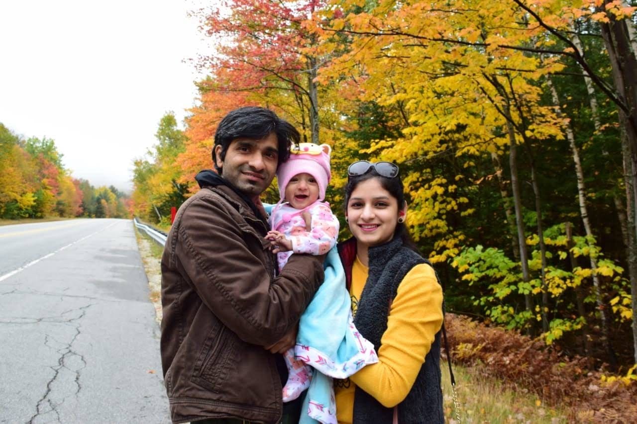 Two parents hug their small child within White Mountain National Park on a glorious fall day.