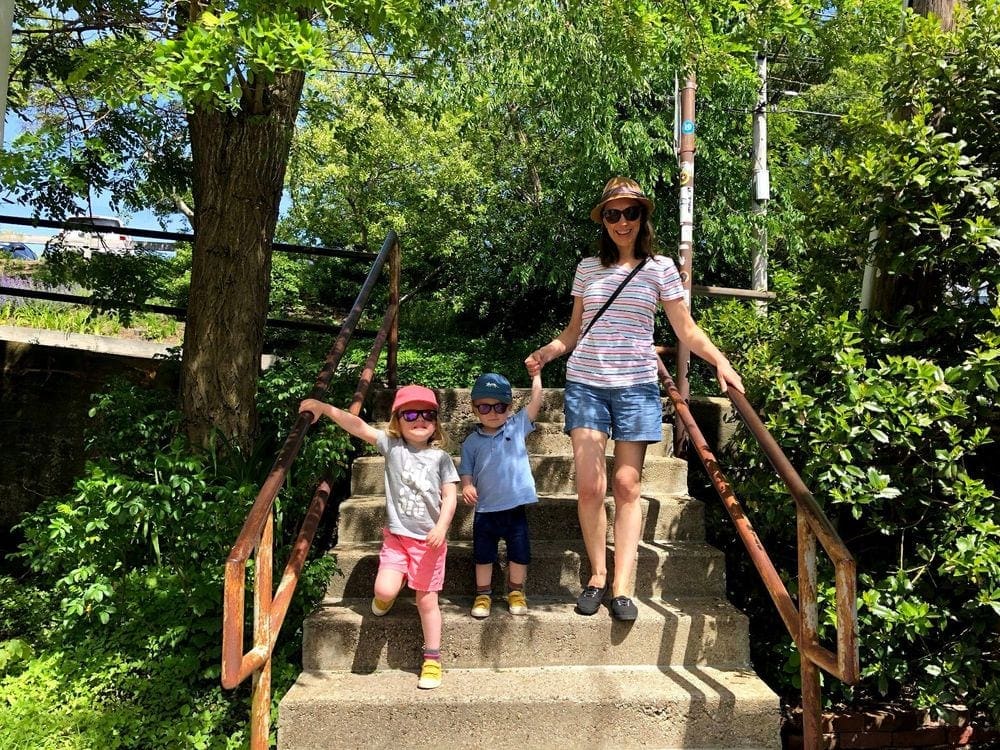 A mom holds the hand of her young son, while her daughter holds the railing as they descend a set of stairs in Proviencetown, Massachusettes, one of the most charming towns to visit with kids.