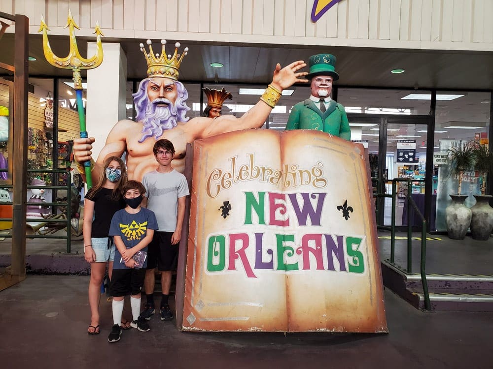 Three kids wearing masks stand near a display at the New Orleans Mardi Gras Museum.